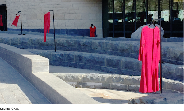 Long red dresses on metal hook scattered on ascending concrete stairway